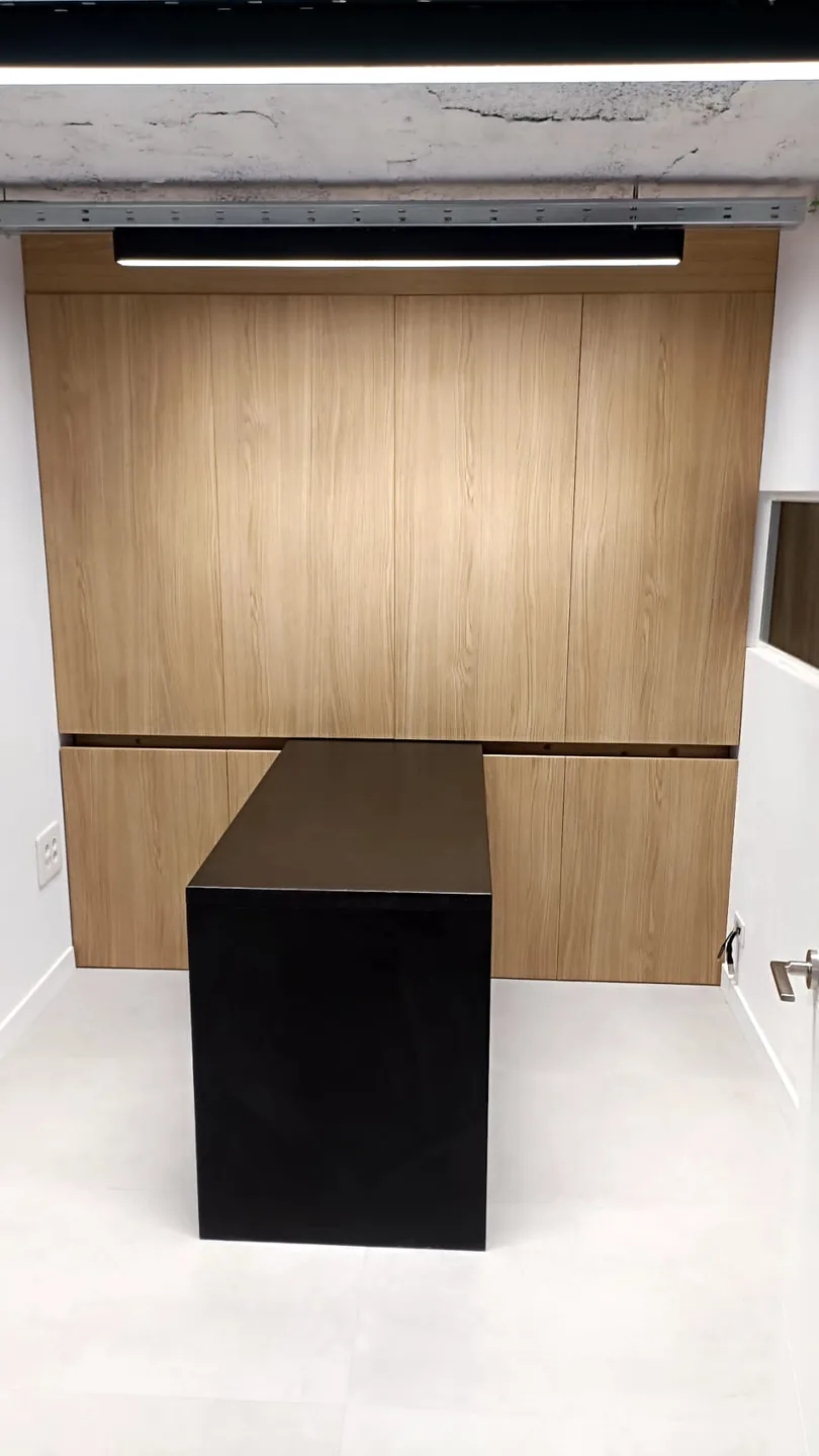Armario de carpinter&iacute;a a medida en roble ocupando la pared completa de una sala de reuniones en Alicante, con mesa lacada en negro