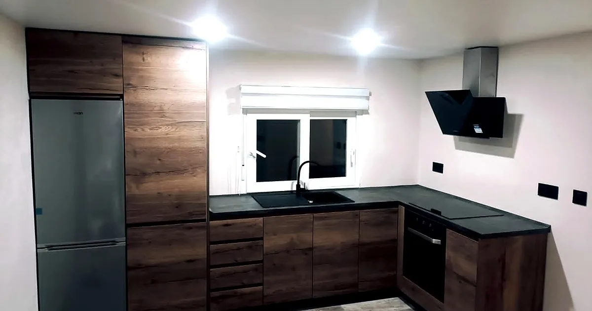 Cocina en roble oscuro con encimera negra y campana decorativa reformada en Alicante